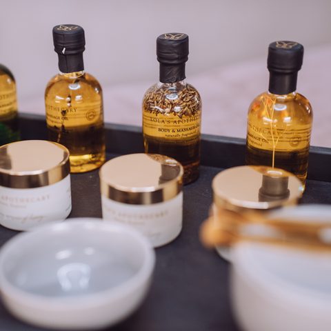 Ölflaschen, Cremedosen und Schalen auf einer Ablage im Wellnessbereich.