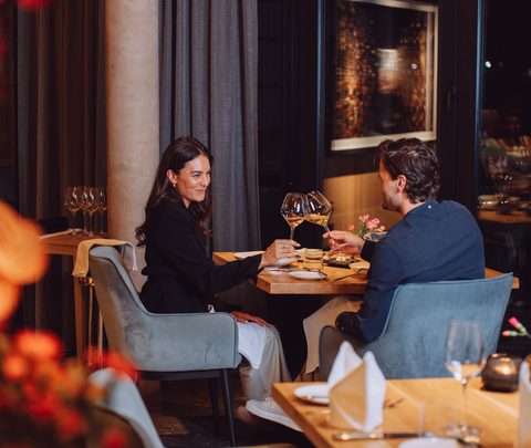 Ein Paar stößt bei einem Abendessen im Restaurant mit Weingläsern an.