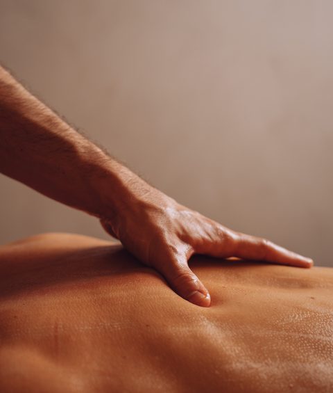 Hand bei einer Massage auf dem Rücken einer liegenden Person in einem Wellnessbereich.