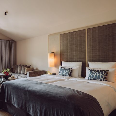 Hotel room with double bed, seating area, and open balcony door.