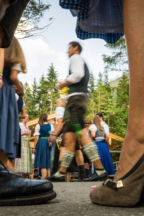 Menschen in Tracht bei einer Veranstaltung im Freien, bodennah mit Fokus auf Beine, Schuhe und Bewegung.