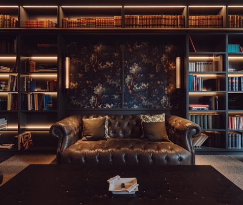 Elegante Hotellounge mit Chesterfield-Sofa, Bücherregalen und warm beleuchteter Bibliothekswand.