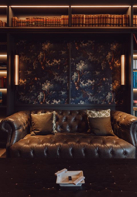 Elegant hotel lounge with Chesterfield sofa, bookshelves and a warmly lit library wall.