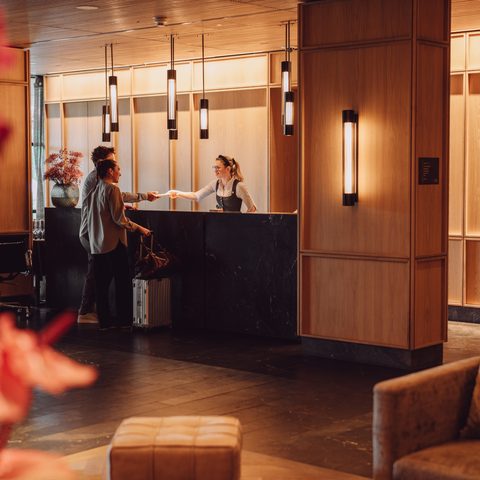 Guest checking in at the reception desk in a warmly lit hotel lobby.