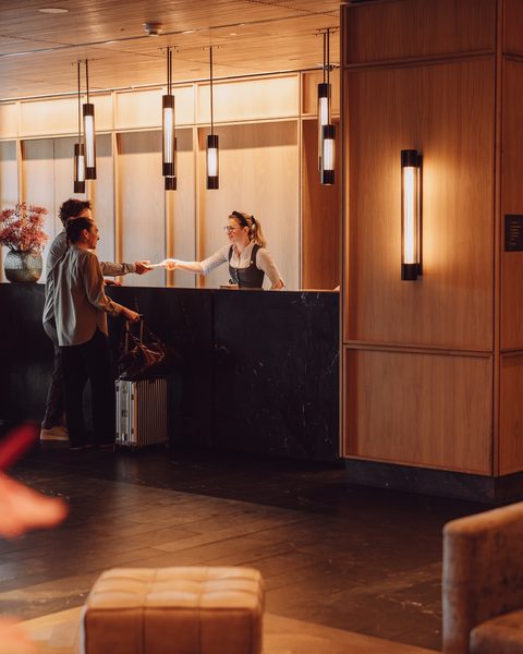 Guest checking in at the reception desk in a warmly lit hotel lobby.
