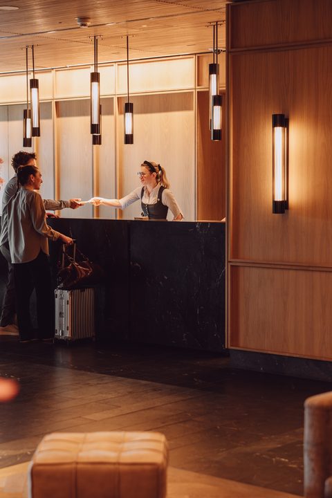 Gast beim Check-in an der Rezeption in einer warm beleuchteten Hotellobby.