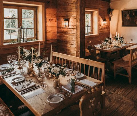 Rustic wooden dining room with set tables, candles and benches in a restaurant.