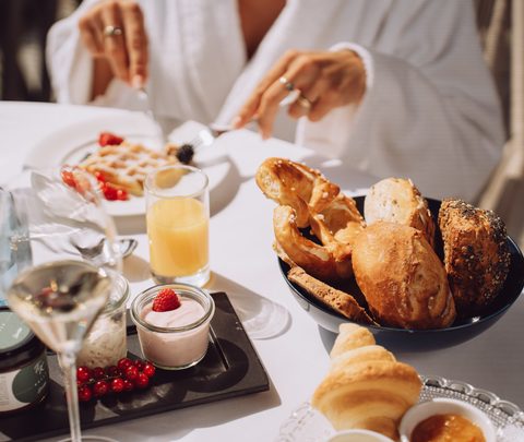 Gedeckter Frühstückstisch mit Brotkorb, Orangensaft, Joghurt und Waffeln im Restaurant.