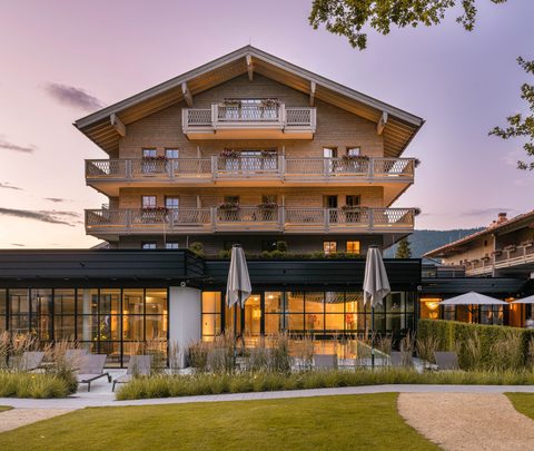Exterior of a hotel with balconies, terrace, and garden at dusk.